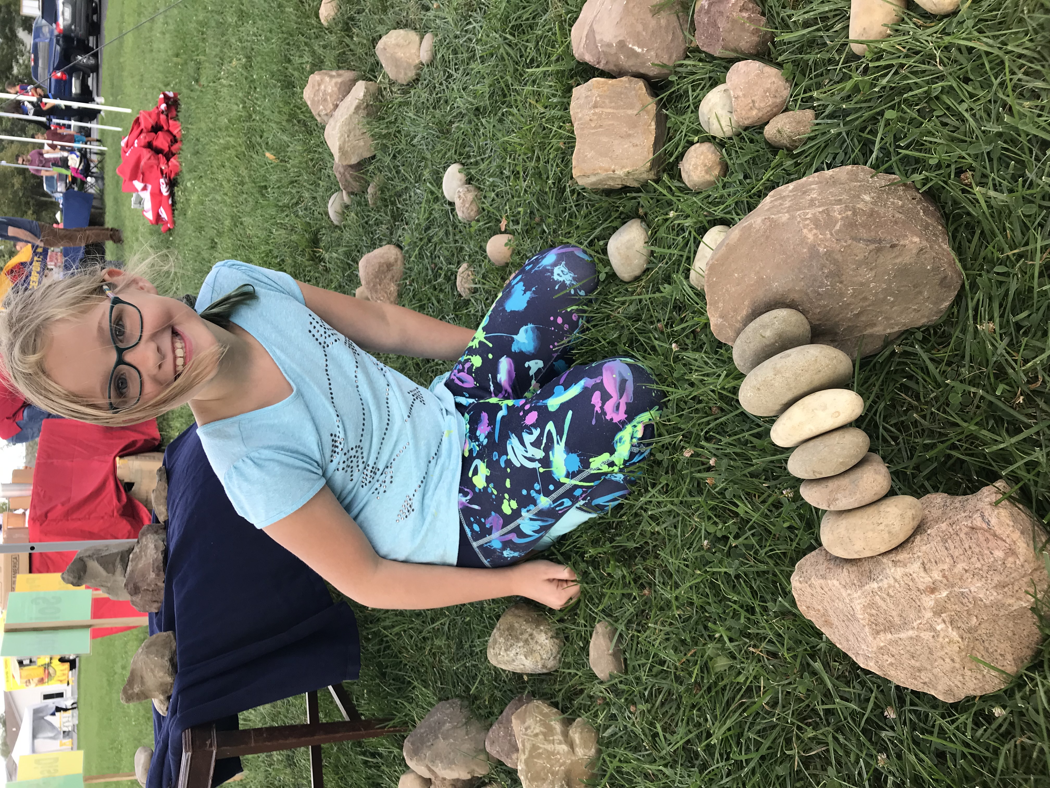 Child smiling behind a stone arch built from river rocks